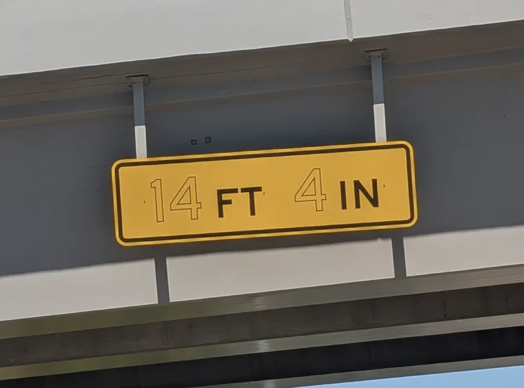 Low clearance sign (MUTCD W12-2a) installed on a bridge where the numbers are drawn in an outline hollowed style.